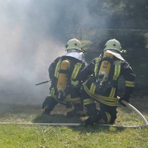 Feuerwehrkameraden löschen ein Feuer.