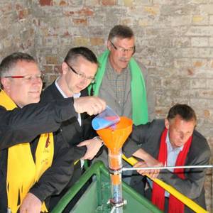 Pfarrer Horst Leischner demonstriert, wie das Granulat entsprechend des Spendenstandes in das Thermometer gefüllt wird.